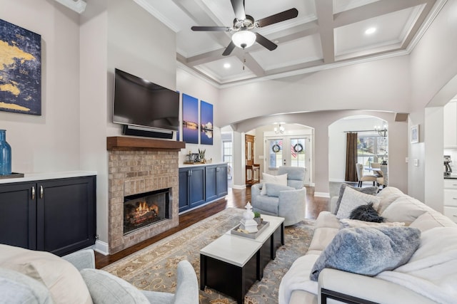 living room with dark hardwood / wood-style floors, a fireplace, ornamental molding, coffered ceiling, and beam ceiling