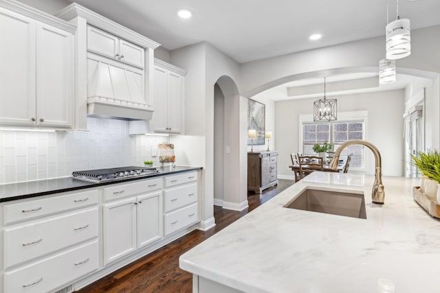 kitchen with decorative light fixtures, sink, and white cabinets