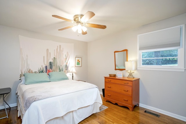 bedroom with a ceiling fan, light wood-style flooring, visible vents, and baseboards