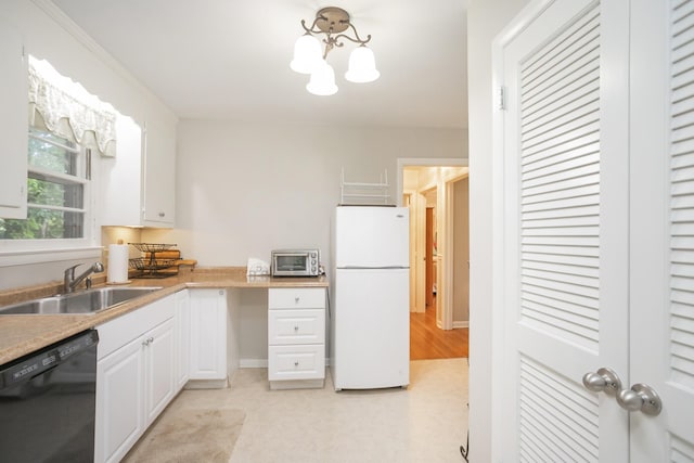 kitchen with a sink, white cabinets, light countertops, freestanding refrigerator, and dishwasher