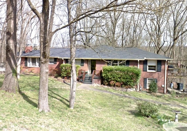 single story home featuring a chimney, a front lawn, and brick siding