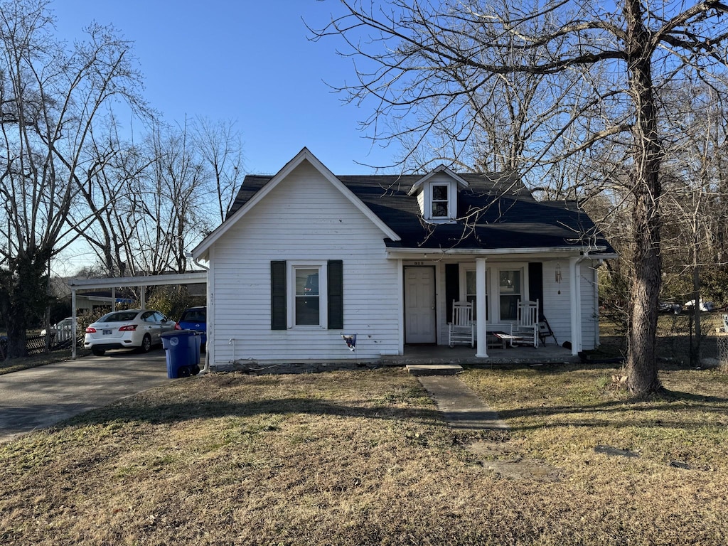 view of front of property featuring a carport, covered porch, and a front yard