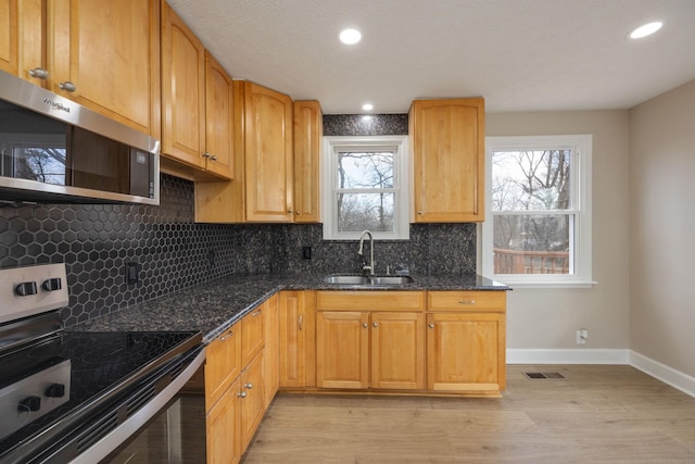 kitchen featuring sink, plenty of natural light, dark stone counters, and appliances with stainless steel finishes