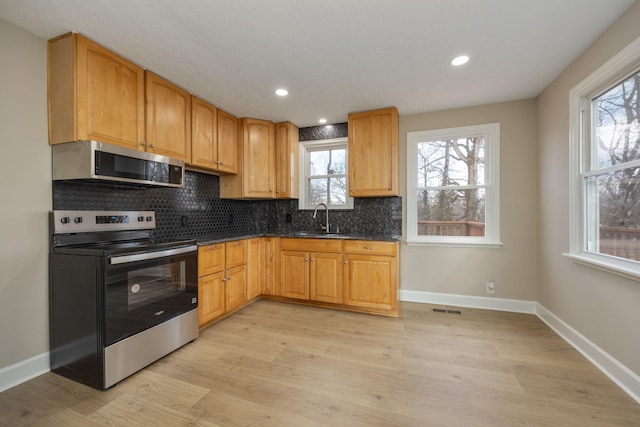 kitchen featuring stainless steel appliances, sink, backsplash, and light hardwood / wood-style flooring