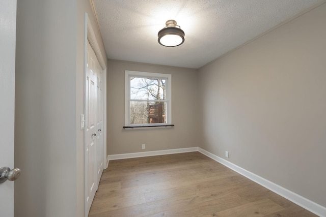 spare room with a textured ceiling and light wood-type flooring