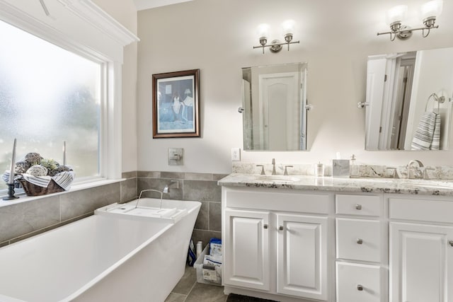 bathroom with vanity, a bath, tile patterned floors, and tile walls