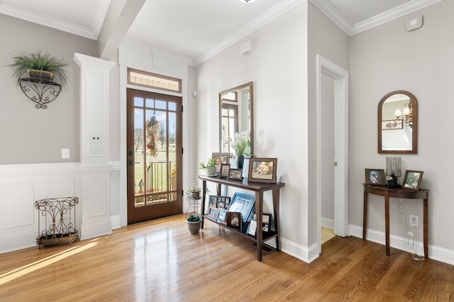 foyer entrance featuring crown molding, wood-type flooring, and decorative columns