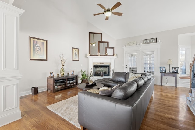 living room with ceiling fan, dark hardwood / wood-style flooring, high vaulted ceiling, and ornate columns