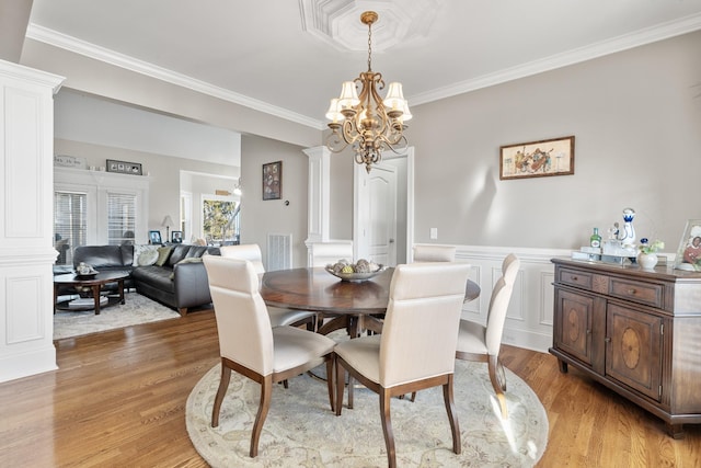 dining area featuring wood-type flooring, crown molding, and an inviting chandelier