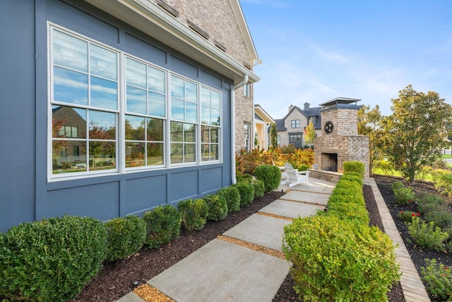 view of yard featuring an outdoor brick fireplace and a patio area