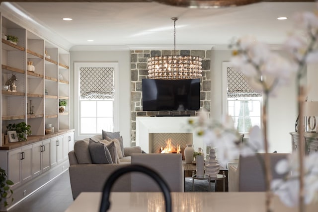 living room with crown molding, an inviting chandelier, and a fireplace