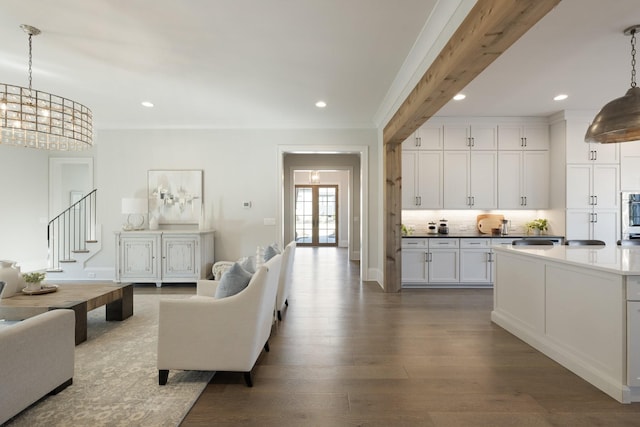 living room with crown molding, wood-type flooring, and a notable chandelier