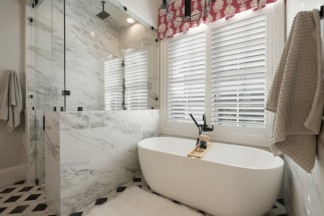 bathroom featuring plus walk in shower, a healthy amount of sunlight, and tile walls