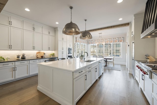 kitchen featuring sink, hanging light fixtures, a center island with sink, appliances with stainless steel finishes, and beam ceiling