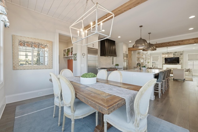 dining space featuring dark wood-type flooring, beam ceiling, a chandelier, and sink