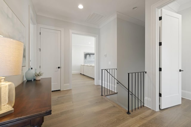 hallway with ornamental molding and light hardwood / wood-style flooring