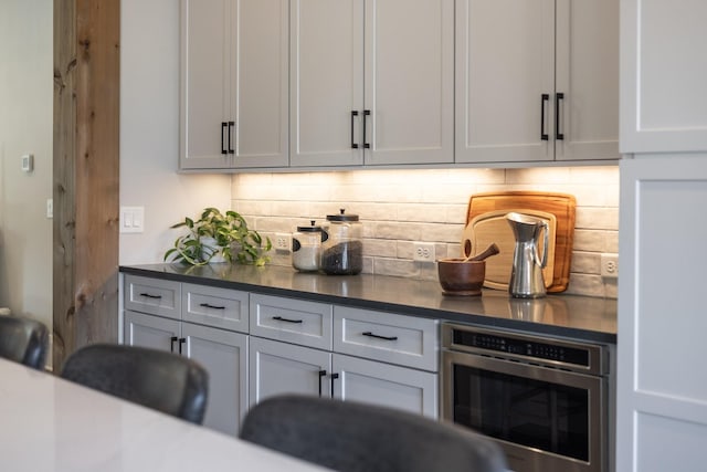 bar with white cabinetry, backsplash, and oven