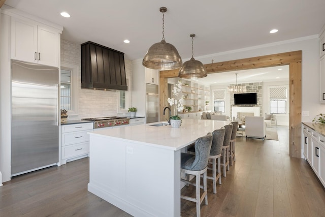 kitchen with white cabinetry, built in fridge, and an island with sink