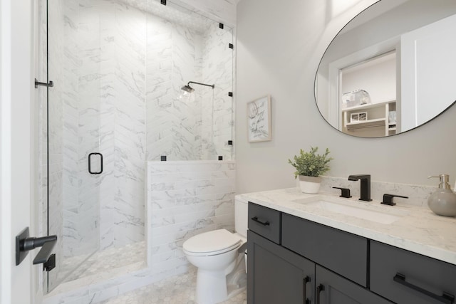 bathroom featuring a shower with door, vanity, and toilet