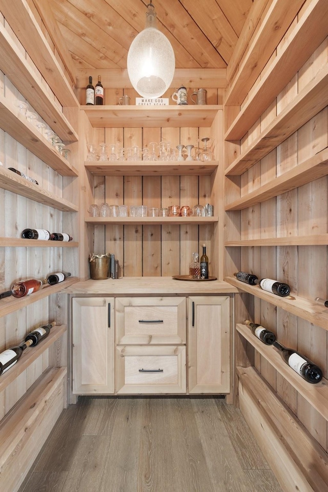 wine cellar with wood walls, light wood-type flooring, and wooden ceiling