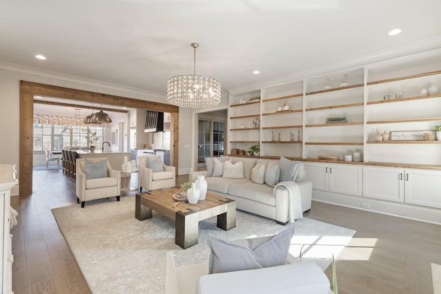 living room featuring crown molding, light hardwood / wood-style floors, and a notable chandelier