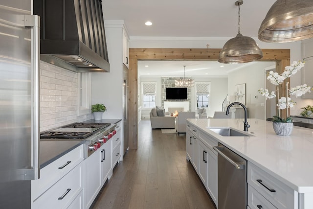 kitchen with wall chimney exhaust hood, sink, white cabinetry, appliances with stainless steel finishes, and decorative backsplash