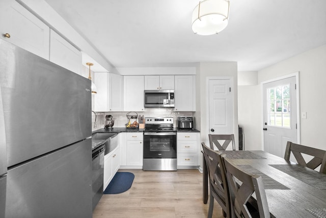 kitchen featuring appliances with stainless steel finishes, tasteful backsplash, white cabinetry, sink, and light hardwood / wood-style floors