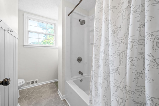 bathroom with a textured ceiling, tile patterned floors, shower / bath combination with curtain, and toilet