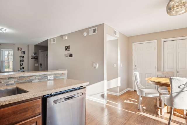 kitchen featuring light stone counters, stainless steel dishwasher, sink, and light hardwood / wood-style floors