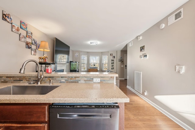 kitchen featuring dishwasher, light stone countertops, sink, and light wood-type flooring