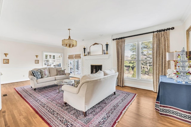 living room with a brick fireplace, crown molding, and wood-type flooring