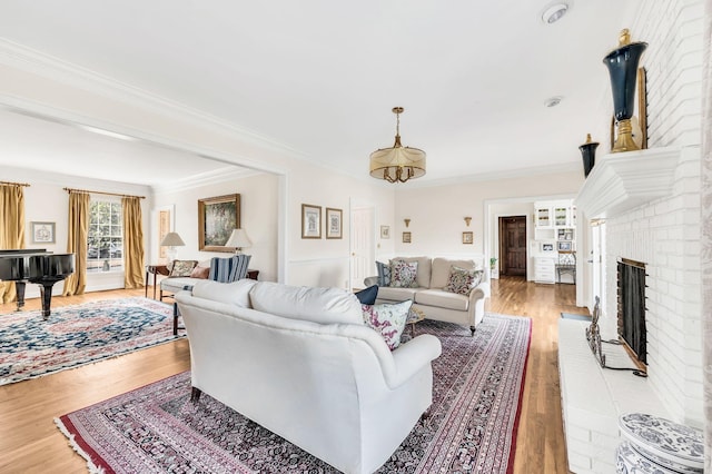 living room with crown molding, a fireplace, and light wood-type flooring