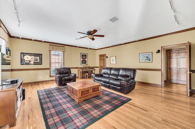 living room with track lighting, ornamental molding, and light wood-type flooring