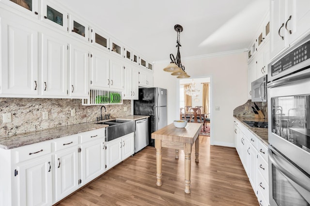 kitchen with stainless steel appliances, white cabinetry, pendant lighting, and light stone counters