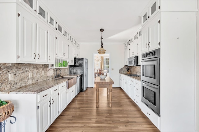 kitchen with light stone counters, stainless steel appliances, decorative light fixtures, and white cabinets