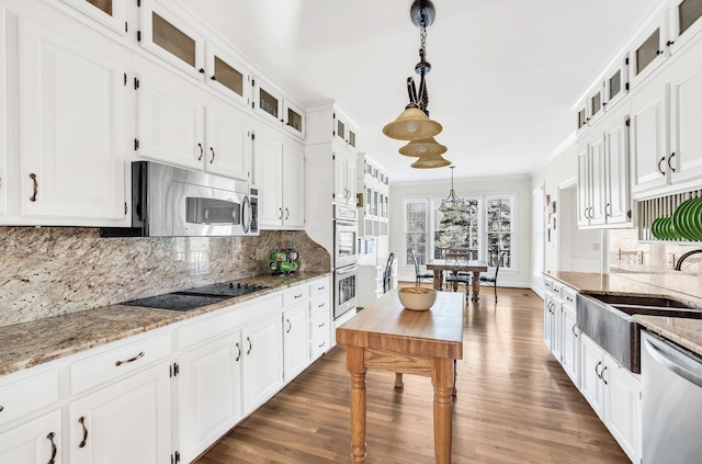 kitchen featuring decorative light fixtures, appliances with stainless steel finishes, light stone countertops, decorative backsplash, and white cabinets