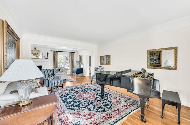 living room featuring a brick fireplace, wood-type flooring, and ornamental molding