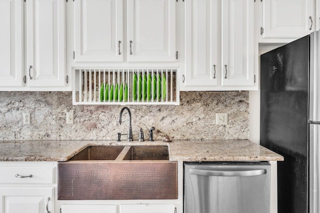 kitchen featuring appliances with stainless steel finishes, white cabinetry, sink, backsplash, and light stone counters