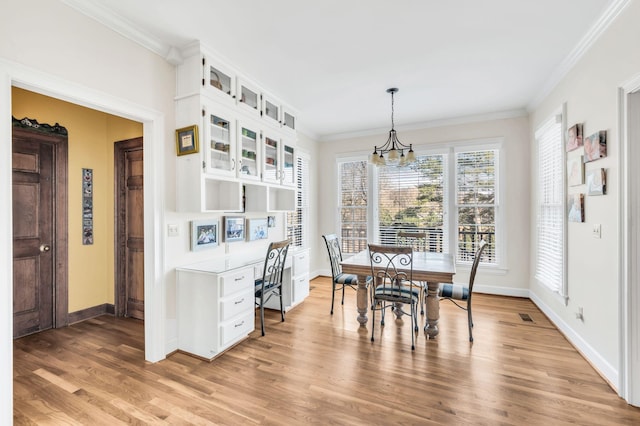 dining area featuring crown molding, an inviting chandelier, and light hardwood / wood-style floors