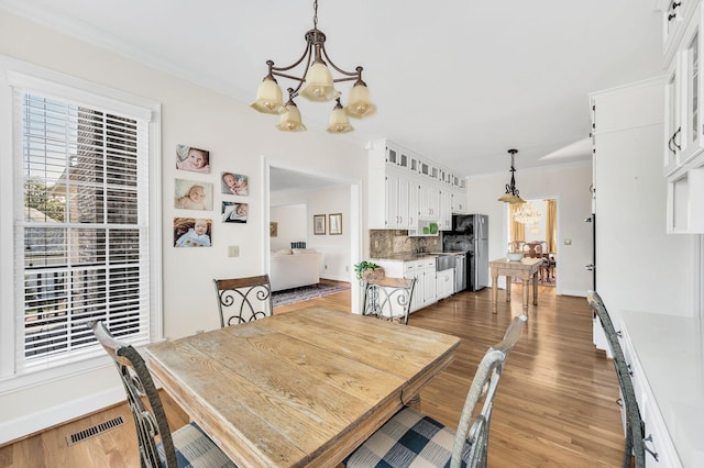 dining room featuring a notable chandelier, crown molding, and wood-type flooring