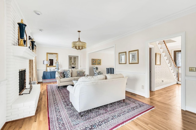 living room featuring crown molding, brick wall, hardwood / wood-style floors, and a brick fireplace