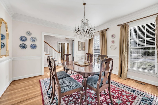 dining area with an inviting chandelier, ornamental molding, and light wood-type flooring