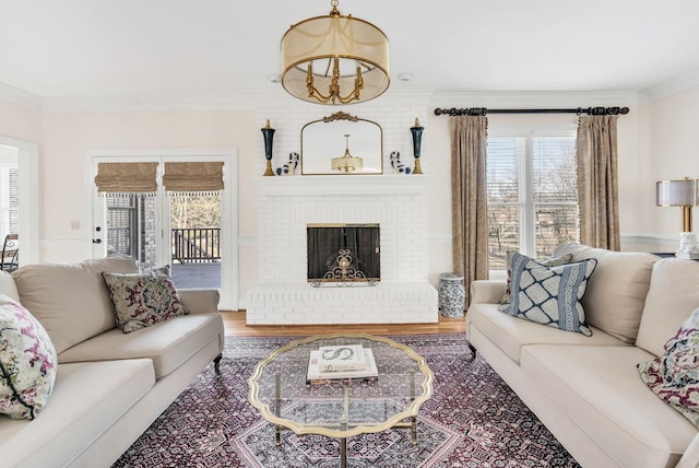 living room featuring crown molding, wood-type flooring, and a brick fireplace