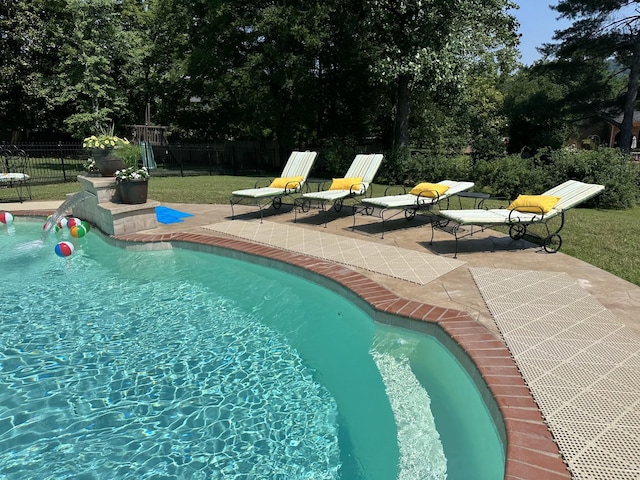 view of pool featuring a lawn and a patio