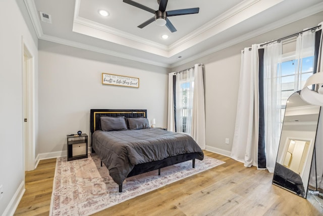 bedroom with a raised ceiling, crown molding, ceiling fan, and light hardwood / wood-style floors