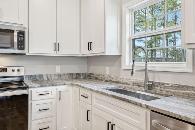 kitchen with stainless steel appliances, sink, and white cabinets