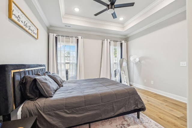 bedroom with crown molding, hardwood / wood-style flooring, a raised ceiling, and ceiling fan