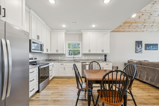 kitchen featuring sink, stainless steel appliances, light stone counters, white cabinets, and light wood-type flooring