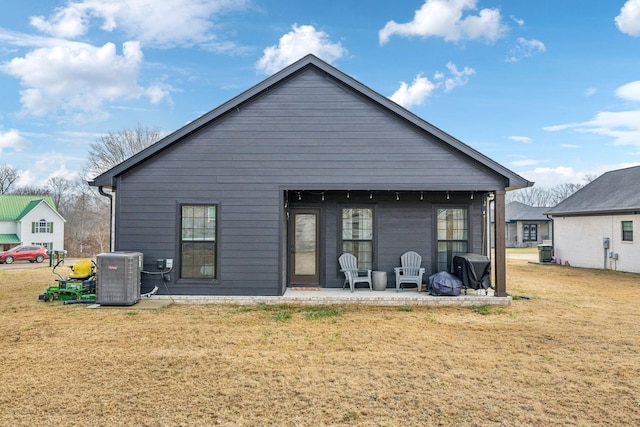 rear view of house with central AC, a patio area, and a lawn