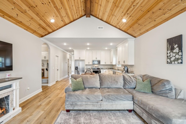 living room with sink, lofted ceiling with beams, light hardwood / wood-style flooring, wooden ceiling, and a fireplace